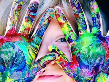 Barn med forskellig maling på indersiden af hænderne